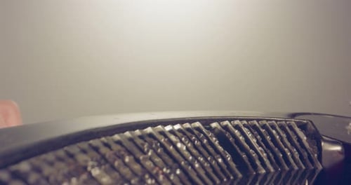 Tiro de plataforma rodante macro especial que se cierne sobre la vieja máquina de escribir con la mano masculina