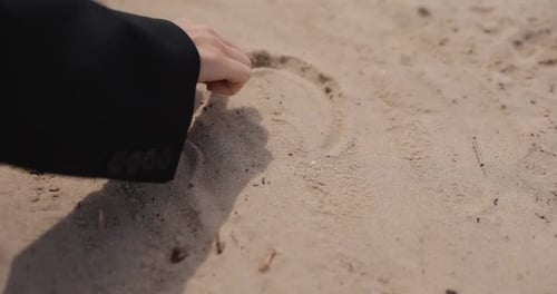 Frau zeichnet Herz am Strand