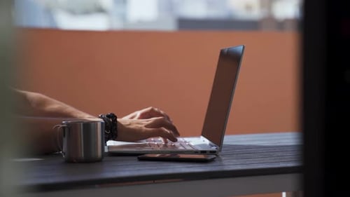 Images en
gros plan d'un homme tapant sur l'ordinateur portable à la table. Travailler à l'extérieur sur le balcon