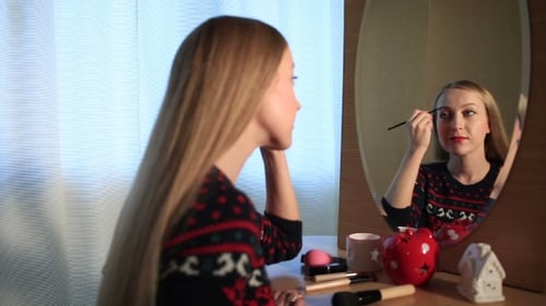 Woman Applying Makeup in Front of Mirror Indoors