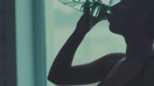 Woman Drinks Water from Bottle After Exercise