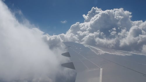 Airplane Wing Flying Through Fluffy White Clouds
