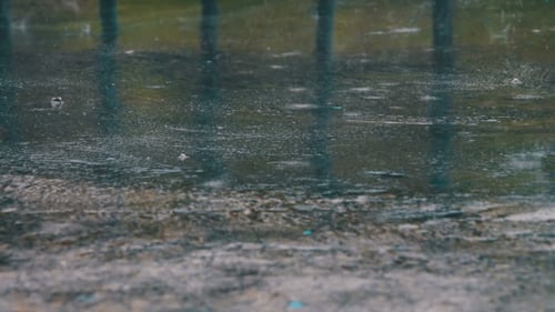 Regen tropft durch die Pfützen
