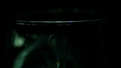 L'eau est versée dans un verre transparent sur fond noir.