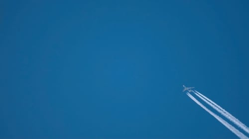 Airplane Soaring Through Blue Sky with Contrails