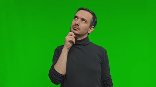 Young Serious Thoughtful Man Put Hand Prop Up on Chin Looks for Solution Options Isolated Green