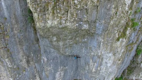 Aerial view of a man rock climbing up a mountain.