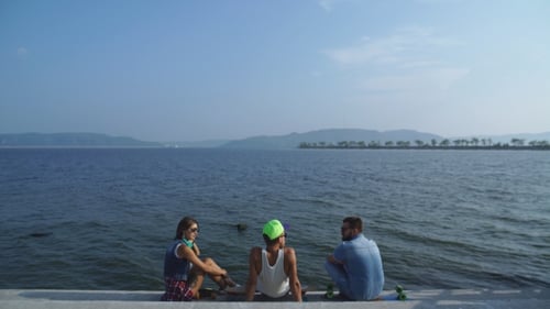 The Group Of Friends With Skateboards Communicate On The Promenade