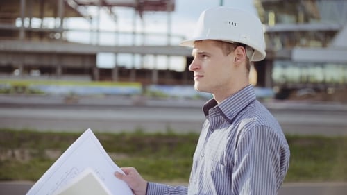 Young Engineer Reviews Plans at Construction Site