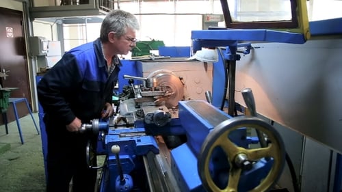 Man Adjusts Industrial Equipment in Factory
