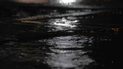 Lluvia charcos y gotas que caen contra las luces de la ciudad del coche