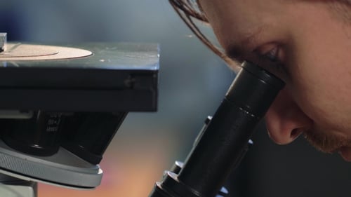 Scientist Looking Through a Microscope In a Laboratory. Young Doctror Diagnostic Shot