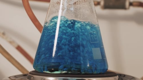 Chimiste en laboratoire tenant le tube à essai pendant la réaction - essai chimique de fer métallique