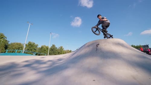 Young Adult BMX Bike Trick at Skatepark on Sunny Day