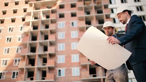 Men Discussing Blueprints on Construction Site
