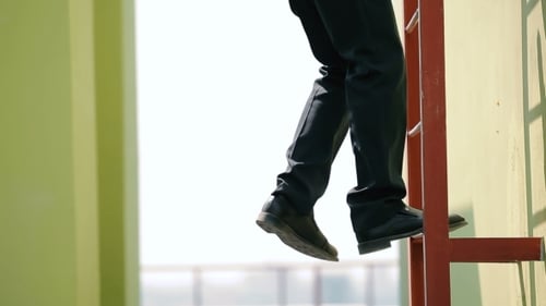 Man Climbing Down Red Metal Ladder on Building