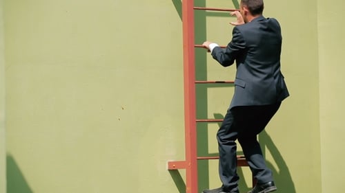 Man in Suit Climbing a Red Ladder