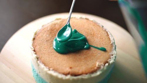 Applying Green Icing To Round Turquoise Cake