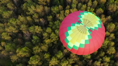 Colorful Hot Air Balloon Floating Over Green Forest