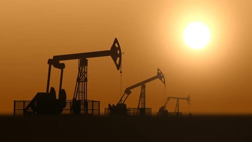 Oil Pump Jacks in the Desert Against Sunset Extracting Crude Oil