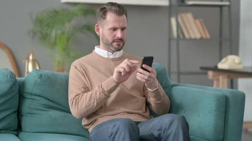 Man Receives Bad News on Phone, Sits on Couch