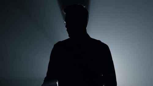 Silhouetted Figure with Handgun in Dark Backlit Room