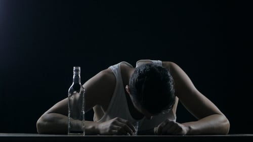 Depressiver betrunkener Typ mit einem Glas Wodka in den Händen senkte den Kopf