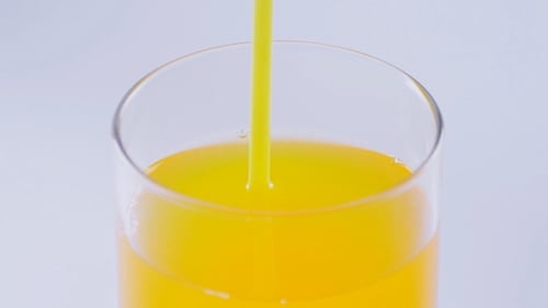 Fresh Orange Juice Pouring into Glass Close-up