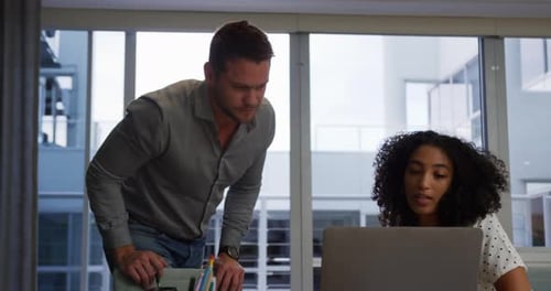 Young office executives discussing over laptop in a modern office