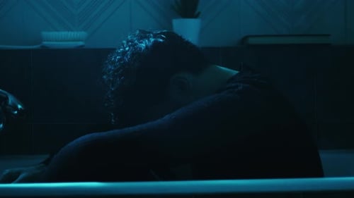 Dark Haired Person Resting in Blue Lit Bathtub