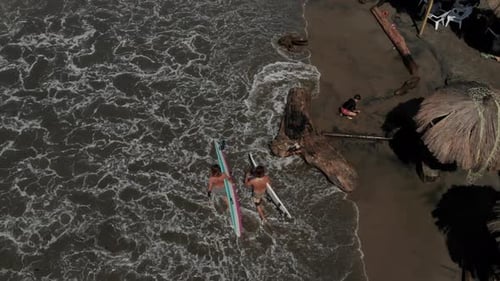 Two Surfers walking on the beach, in Colombia.