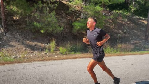 Man Running Along Forest Road in Daylight