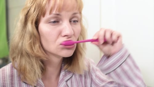 Woman Brushing Teeth in Bathroom Mirror Close Up