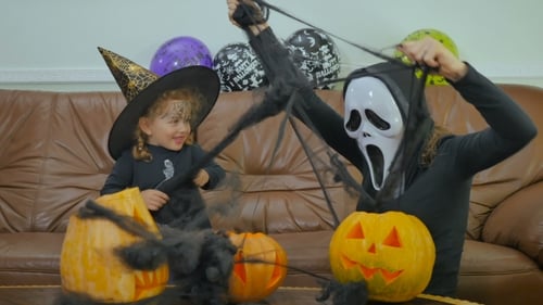 Mulher com máscara assustadora brinca com garota no Helloween