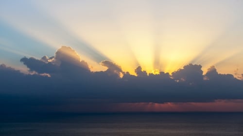 Sun Rays Emerging Though The Clouds At Sunrise Over Sea.