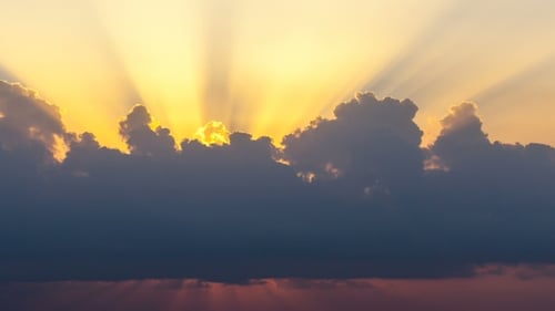 Sonnenstrahlen tauchen bei Sonnenaufgang über dem Meer durch die Wolken auf.
