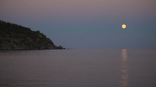 Beautiful Night Scene With The Full Moon Rising Over Sea With a Lunar Path