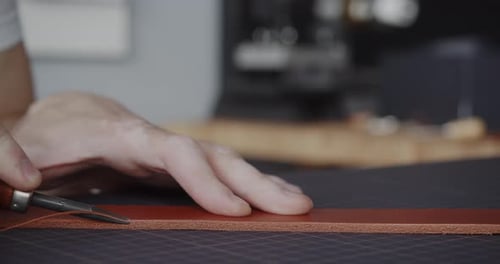 Leatherworker Smoothing Edge of Leather Strip with Tool