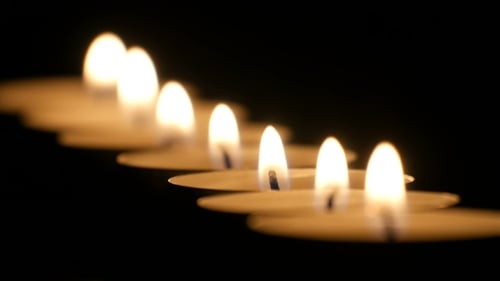 Row of Candles Flickering in the Darkness