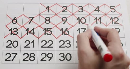 Crossing Off Dates on a Calendar with Red Marker