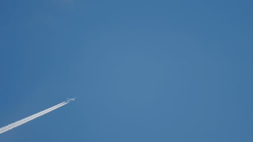 Airplane Flying Leaving Contrail Across Blue Sky