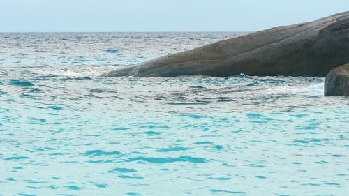 Turquoise Water Flowing Gently Near Rugged Rocks