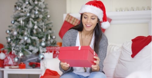 Woman Opening Christmas Gift by Decorated Tree