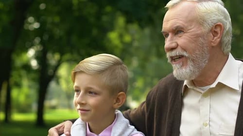 Grandfather Showing His Grandson Something in Park, Enjoying Free Time Together