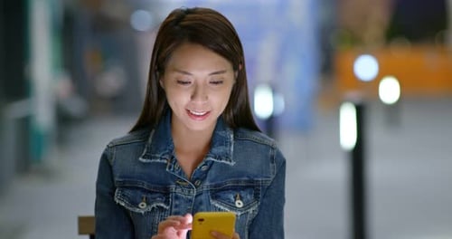 Woman Uses Phone at Night in City