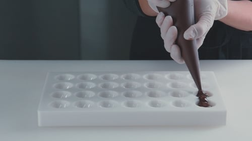 Chocolate Being Piped Into Candy Mold Cavities