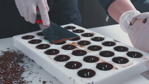 Hands Smoothing Dark Chocolate into Candy Mold