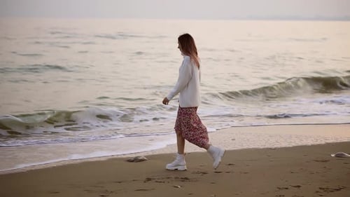 Girl in Elegant Clothes Walks Along the Seashore View From the Side