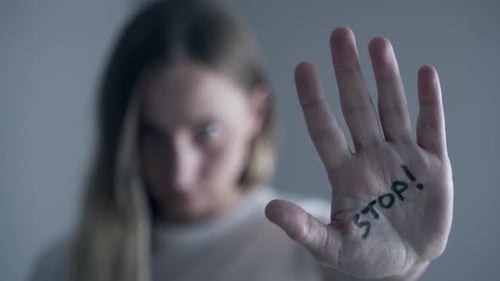 Frau mit Prellungen im Gesicht zeigt Stoppschild, Handfläche im Fokus
