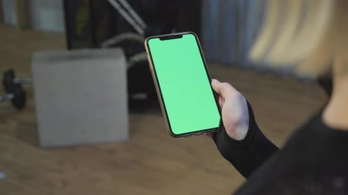 A Young Athletic Woman Holds A Smartphone in Her Hand, Shows A Green Chromakey Screen